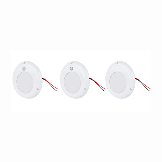 Three white LED puck lights with wires on a white background